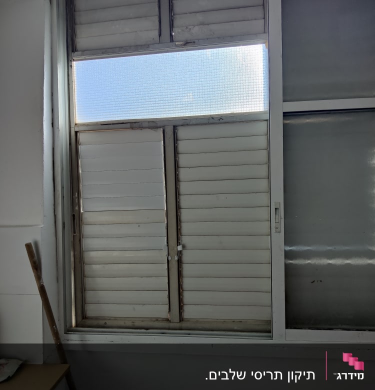 תריסים לבנים סגורים עם חלון זכוכית עליון